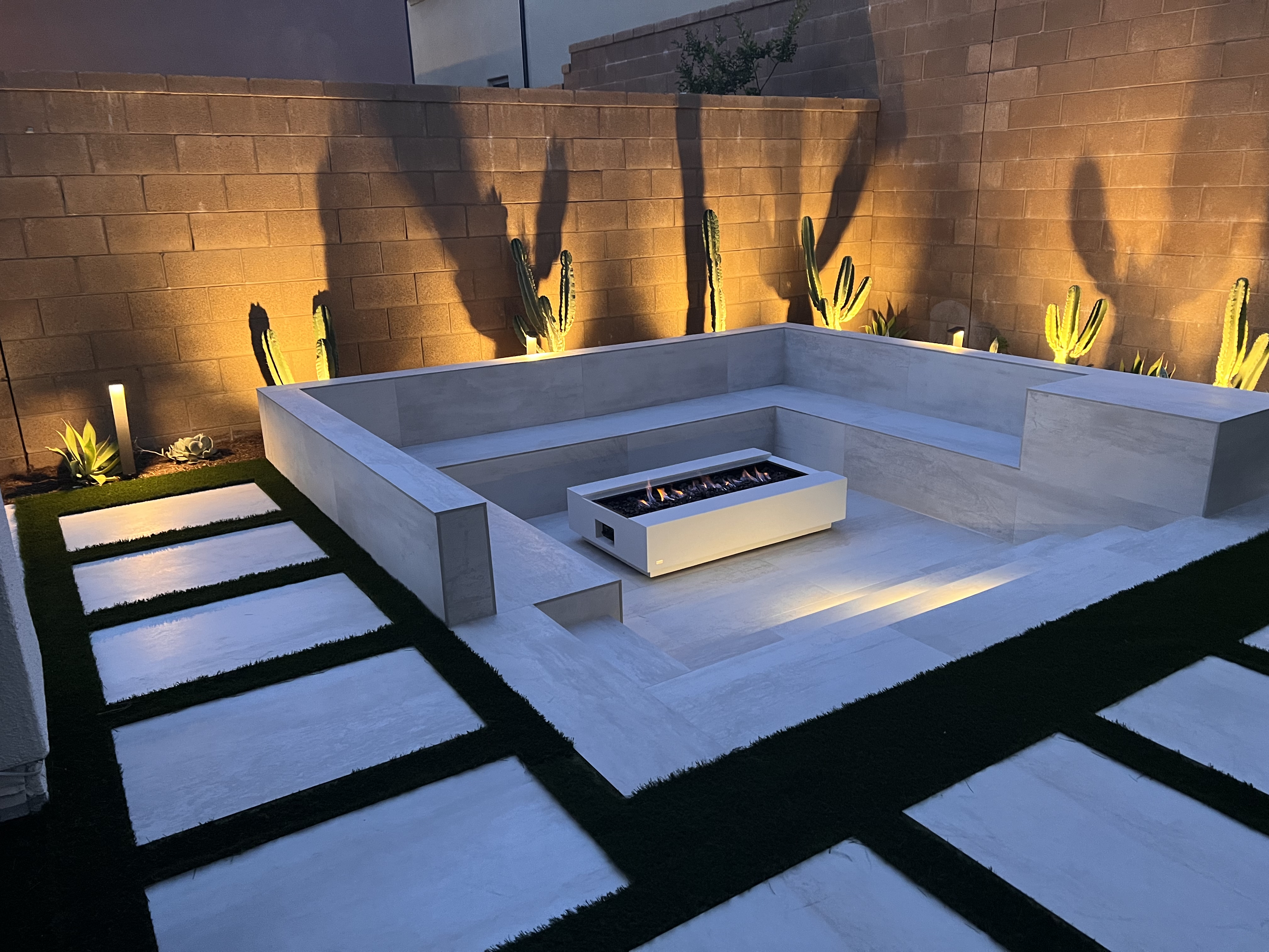 Sunken fire pit lounge among cacti at dusk